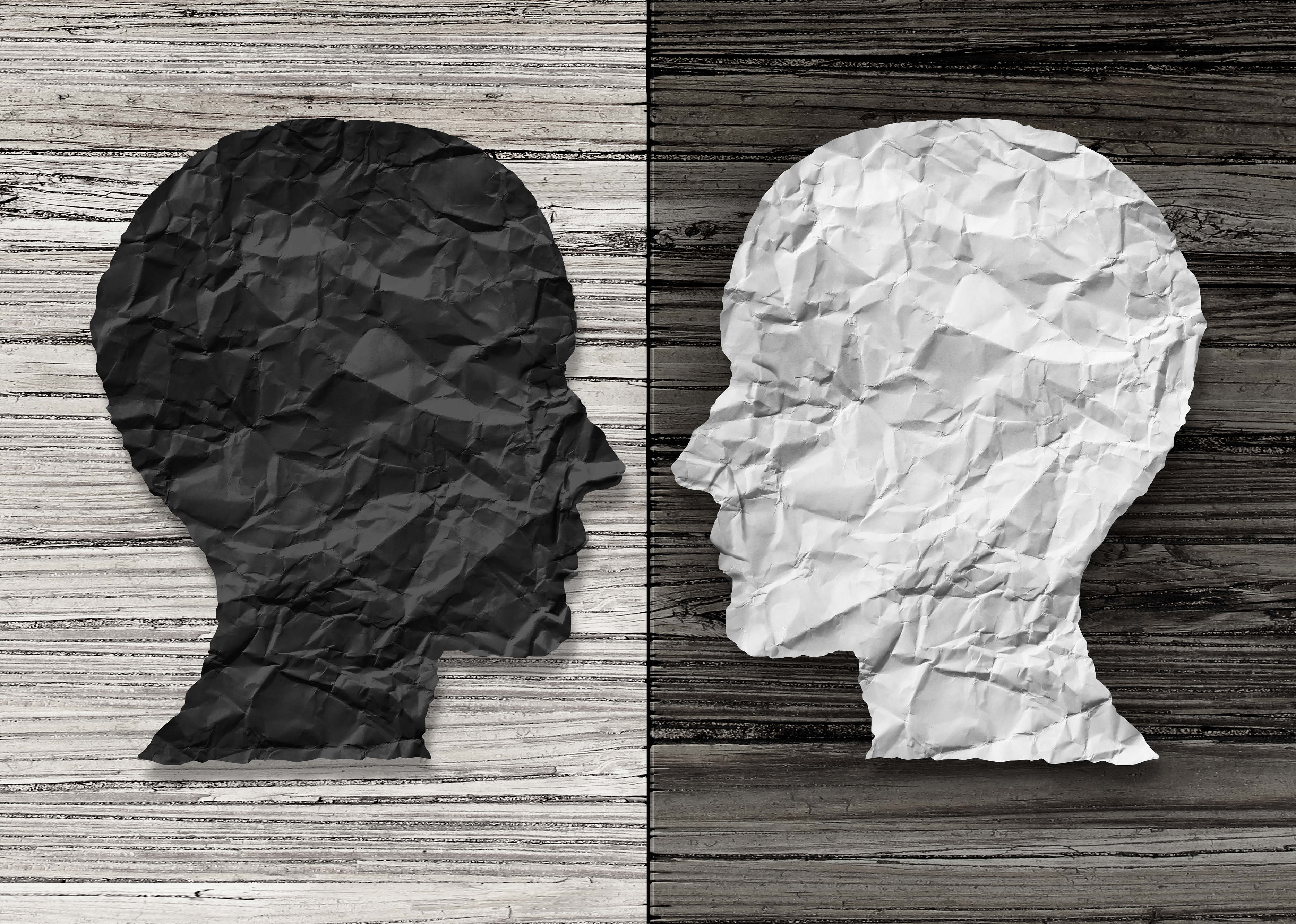 Two sillhouetted faces in profile facing each other. One is made of black paper, the other is made of white paper.